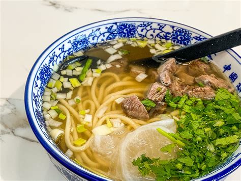  Hand-Pulled Lanzhou Noodles: Een Smaaktontploffing van Gebraden Aromatische Kruiden en Licht Gefermenteerde Zuren!